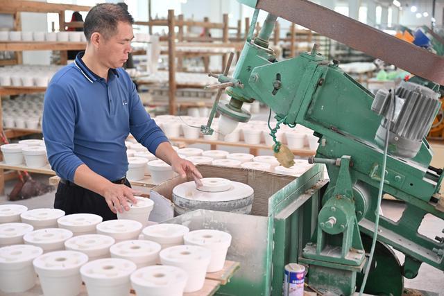 10月21日,在福建省泉州市德化县顺美陶瓷厂,工人操作机器制作陶瓷产品